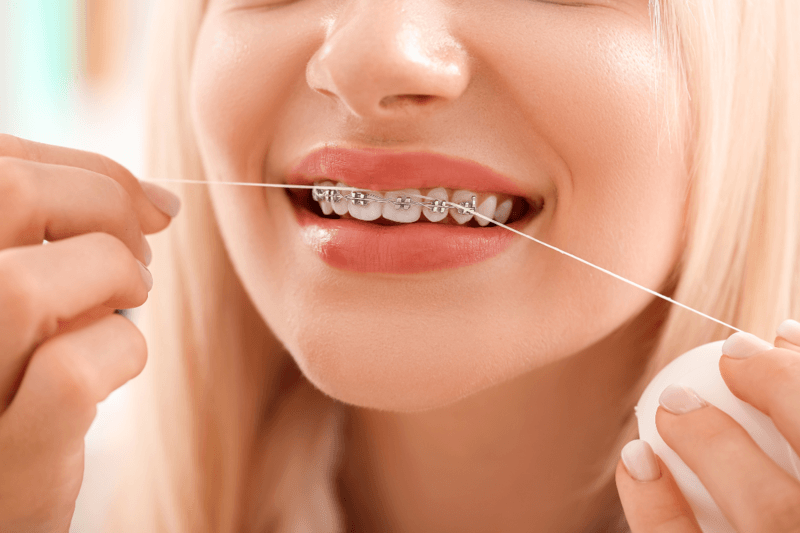 Young girl with braces flossing her teath